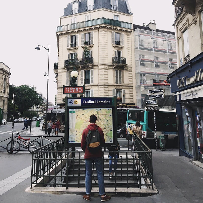 a man standing in front of a board with the city map, with classical parisian architecture at the back, by tayylin.com