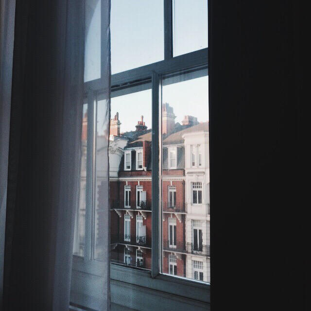 european-style architecture seen through half-closed curtains in london at dawn, by tayylin.com